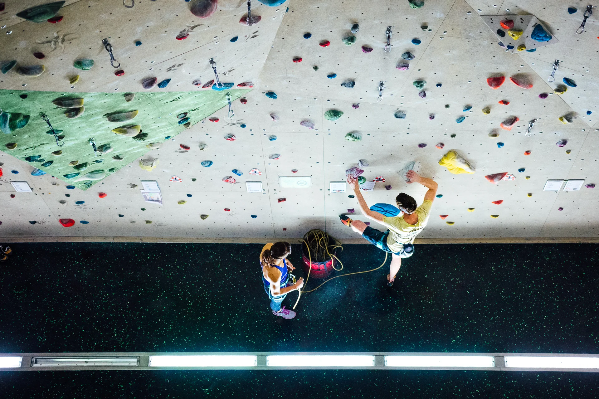 Kletterer beim Seilklettern an der Wettkampfwand und Frau, die ihn sichert | © diekletterarena Wettkampfwand Sichern | © diekletterarena