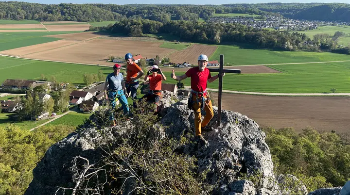 Gruppe von Menschen beim Klettern auf einem Fels mit Gipfelkreuz | © DAV Heilbronn